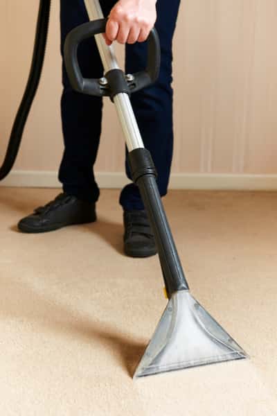 This is a photo of a man steam cleaning a cream carpet, using a professional steam cleaning machine works carried out by Ruislip Carpet Cleaning Solutions